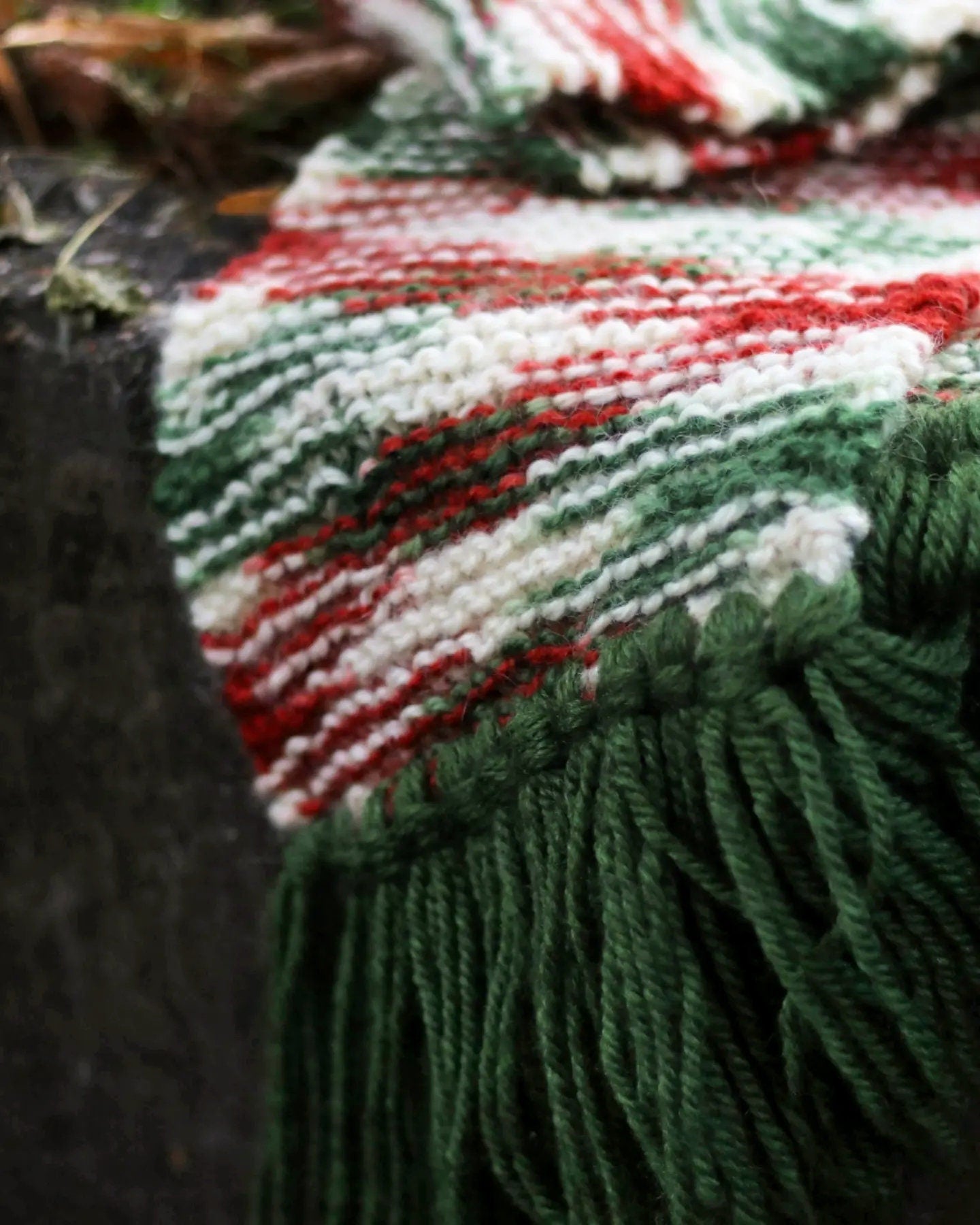 Close-up of a maximalist winter scarf featuring bold green fringe and a cozy chunky knit texture