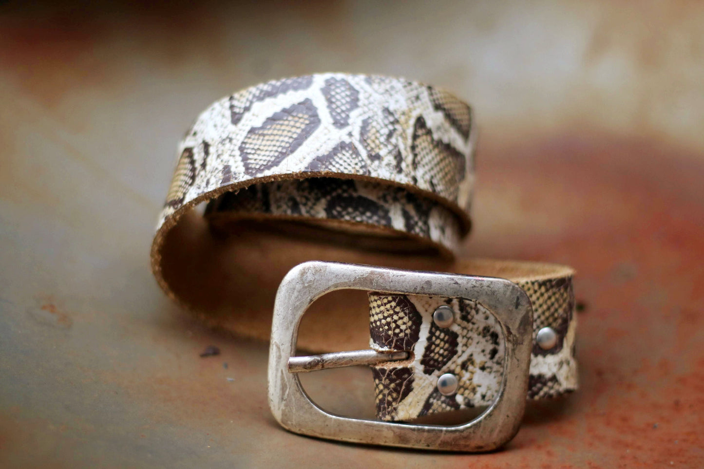Close-up photo of a fashionable snake print leather belt with a vintage metallic buckle. Perfect accessory for trendy outfits and stylish looks.