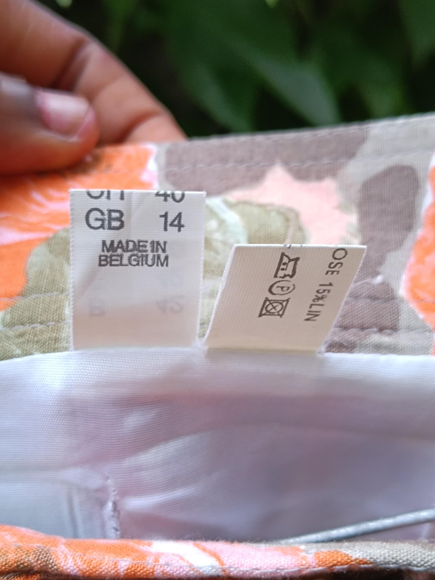 Two size tags of a 80s Floral Skirt are visible. One highlights the size of vintage skirt in different countries and the other provides care instructions for the bold summer design