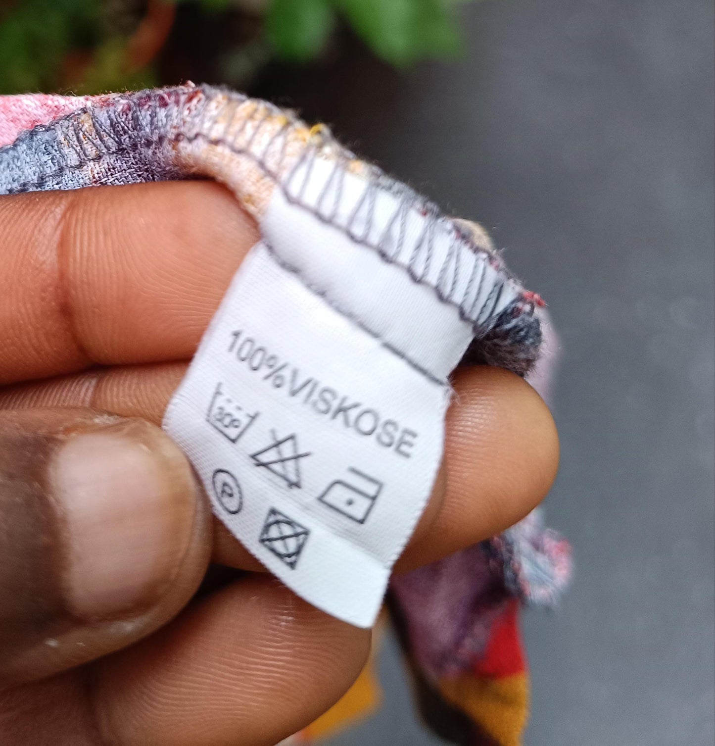 The white fabric tag of a Montino tropical floral shirt. The tag reads "100% viscose" care instructions with symbols are also visible