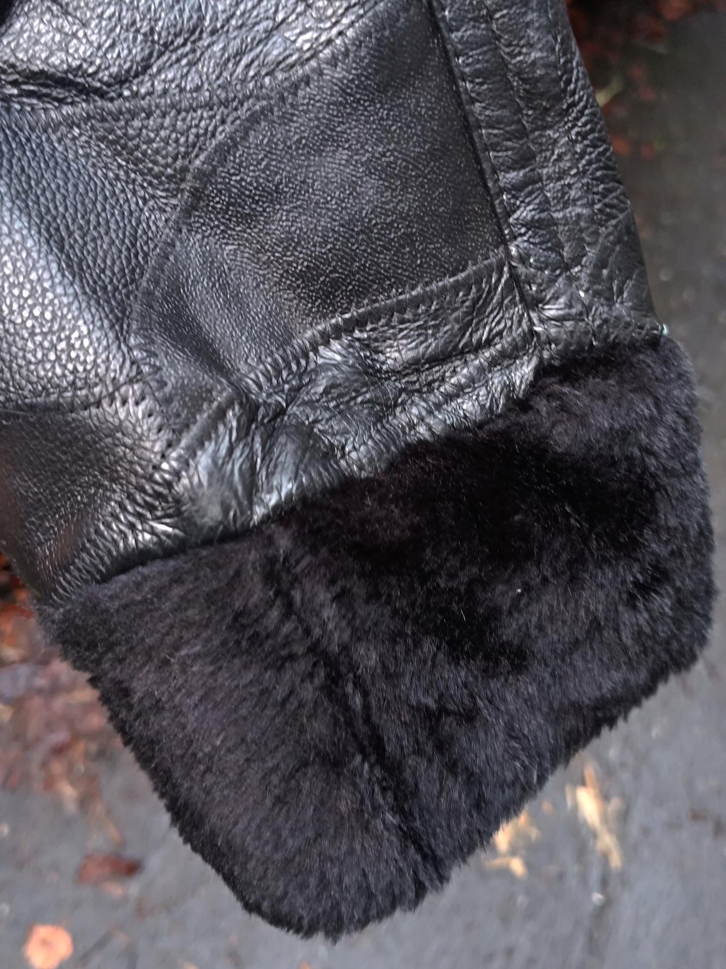 A detail shot of the sleeves of a vintage black leather jacket with a faux fur trimmings. The jacket is by the brand Anne De Lancay Women