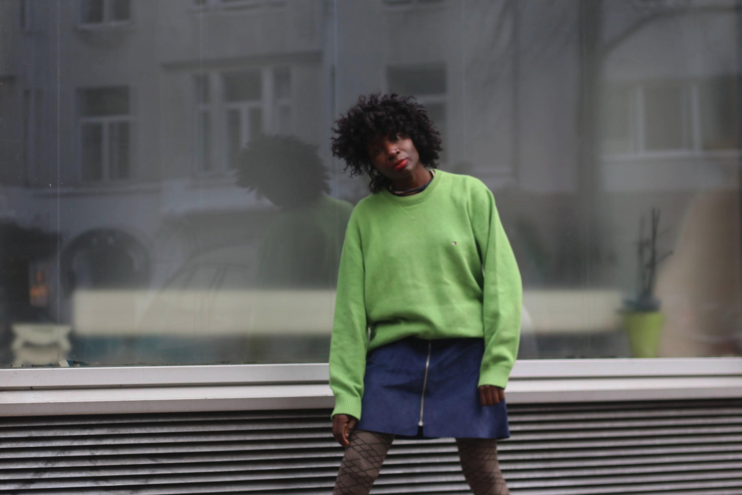 A person wearing a green sweater and a vintage dark blue suede mini skirt.