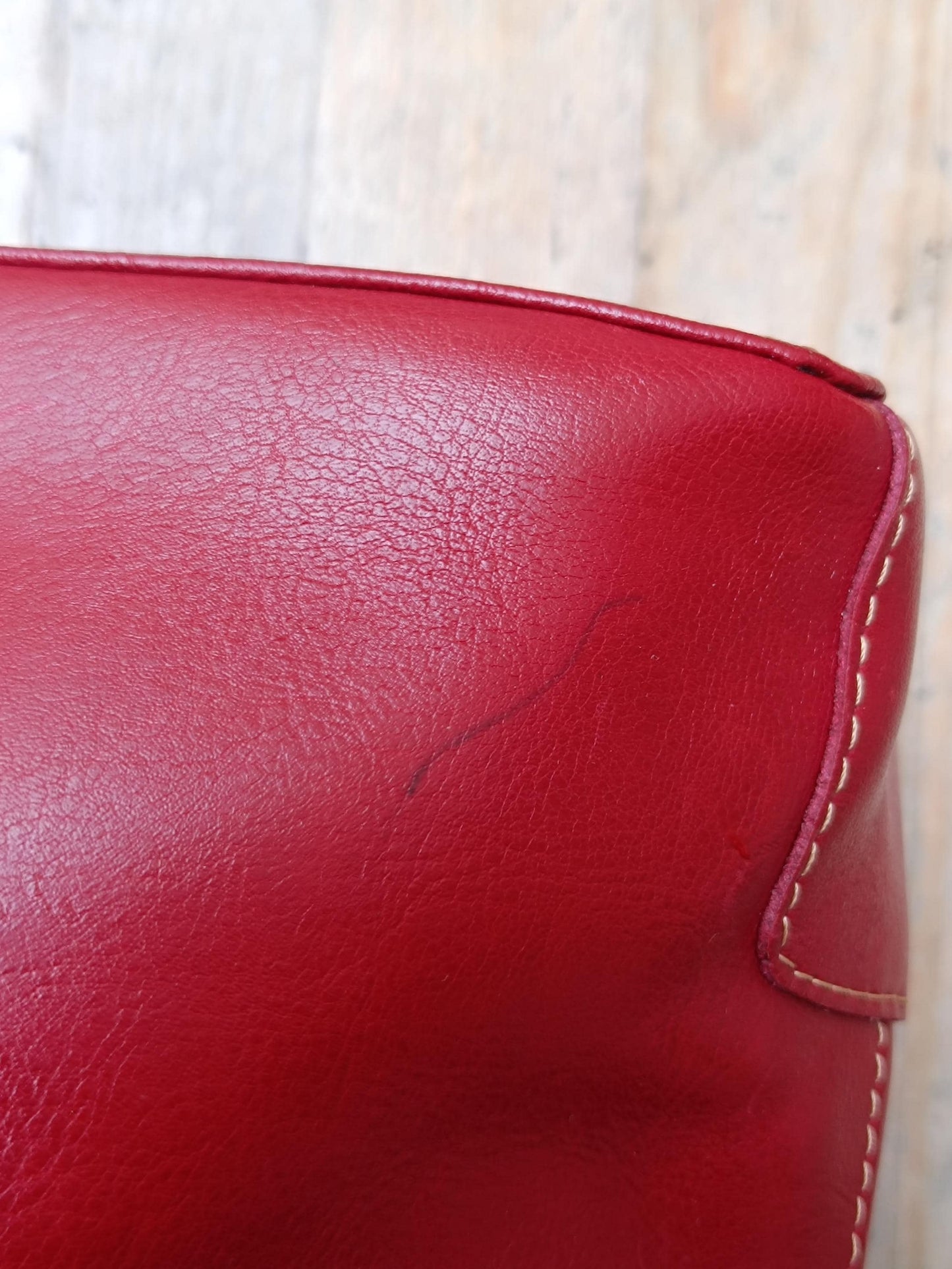 Close-up of a red leather shoulder bag showcasing the one sign of vintage wear: a small pen mark.