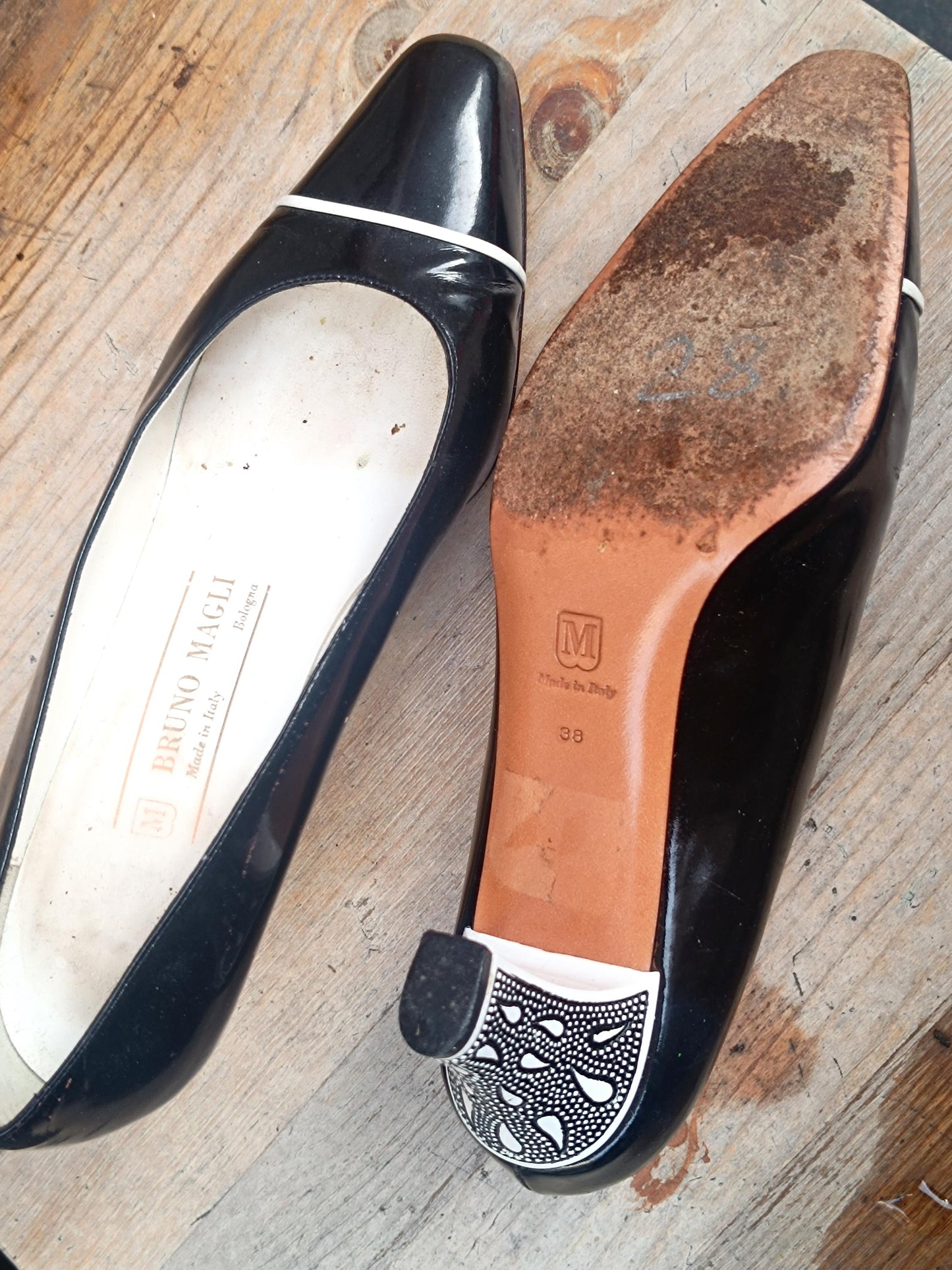 80s Retro designer pumps by Bruno Magli photographed against a minimalist background. the heel is visible on one shoe and on here is the size details and leather composition