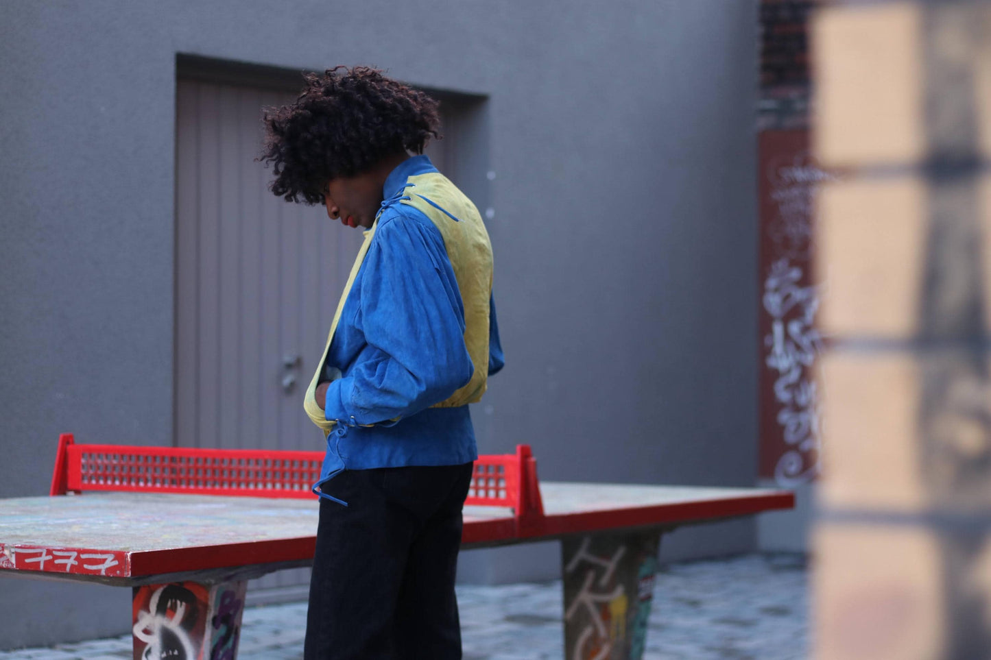 A fashion-forward look featuring a vintage statement suede jacket in electric blue and soft yellow, styled with dark denim.