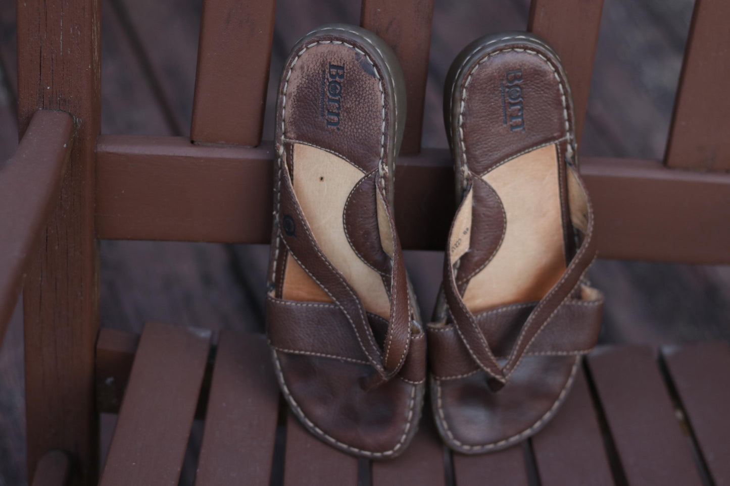 Vintage Retro Børn designer sandals with a relaxed, broken-in aesthetic photograhed on a wooden brown chair outdoors.