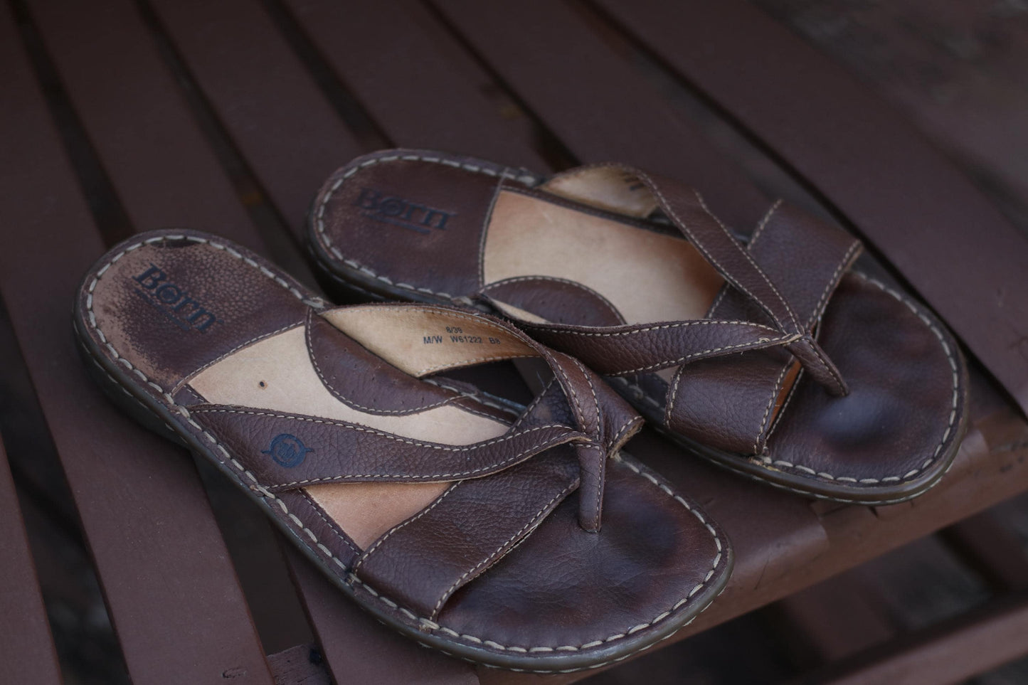Vintage 90s Børn women's brown leather sandals with unique cross-foot straps photograhed outdoors on a brown wooden chair