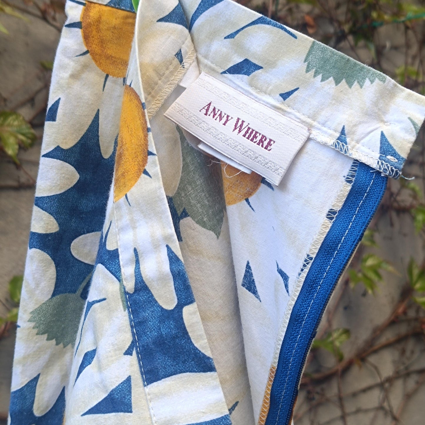 Close-up of a white fabric skirt with a blue and yellow floral daisy pattern, showing the waistband and a "ANNY WHERE" tag