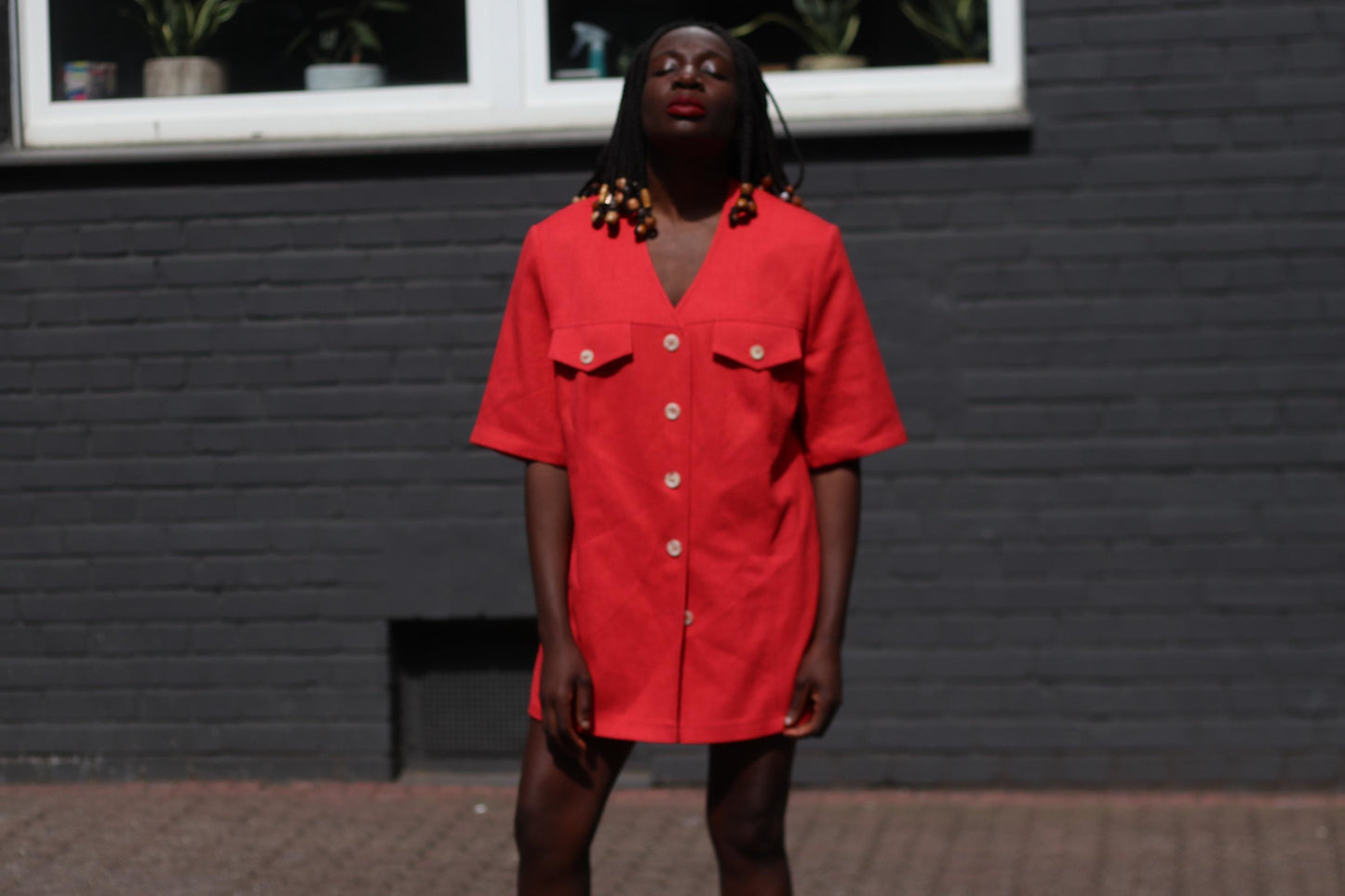 Female model in a vintage 90s Short-Sleeved Blazer by Mark Wald worn as a mini dress photographed in front of a grey brick wall. The image highlightd the bold v-Neck Jacket as a lightweight versatile retro piece