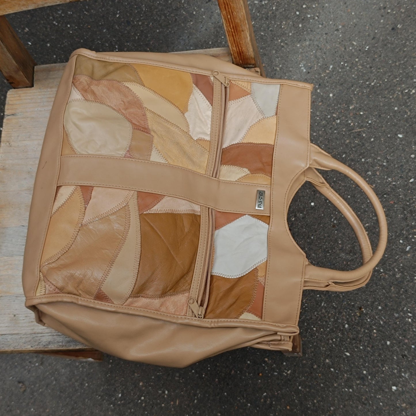 An artistic flat lay of a vintage brown leather patchwork top handle bag from the 79s photographed top down on a rustic brown chair outdoors