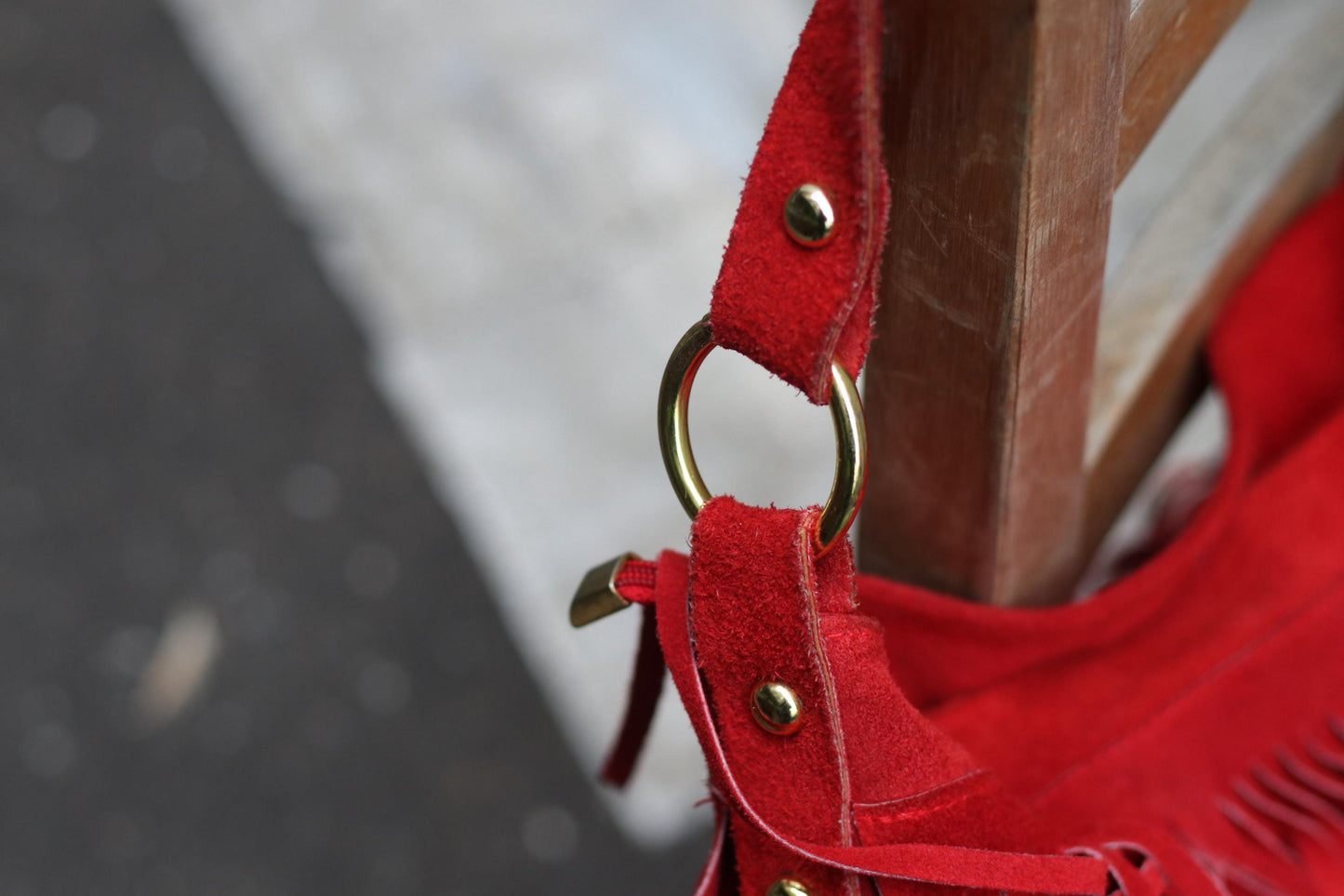 Detail shot of the gold-toned hardware of a handcrafted vintage suede purse with gold rings and bold fringe.