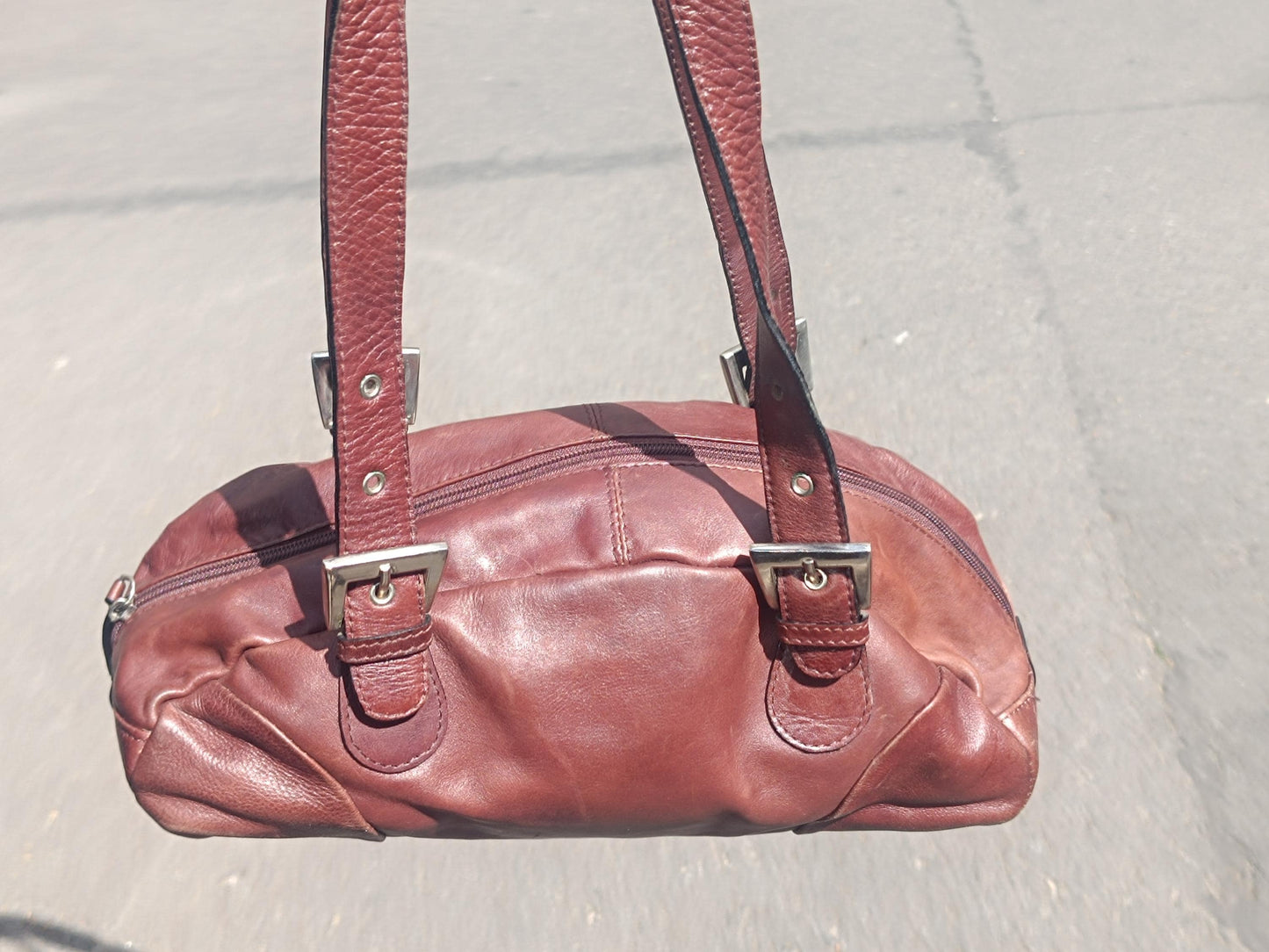 Vintage y2k brown leather handbag with sculptural shape and silver hardware, styled against neutral backdrop.