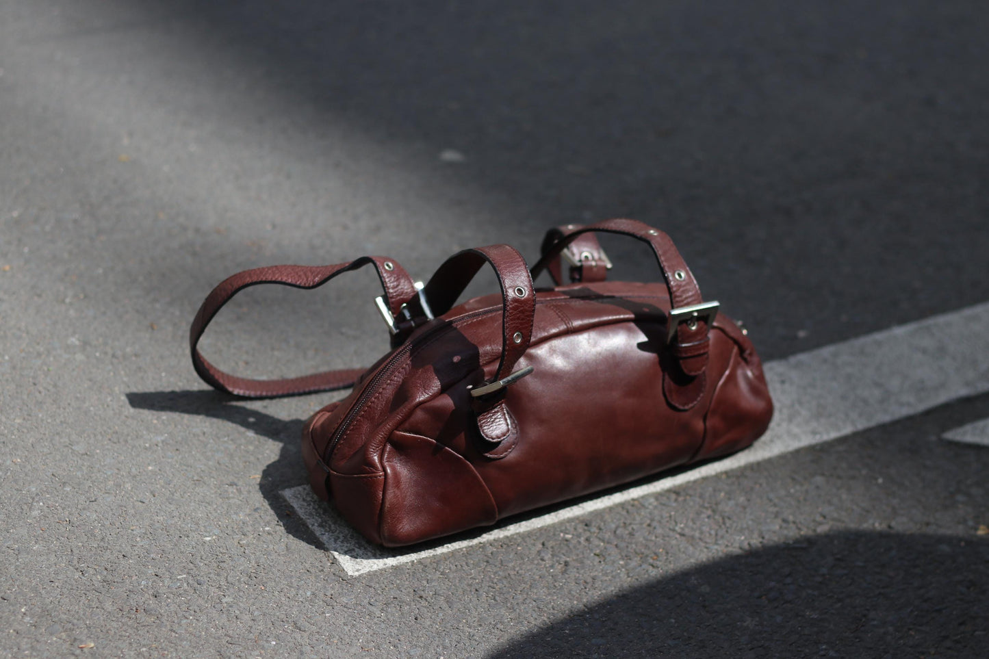 Vintage brown leather handbag with sculptural shape and silver hardware, styled against neutral backdrop.