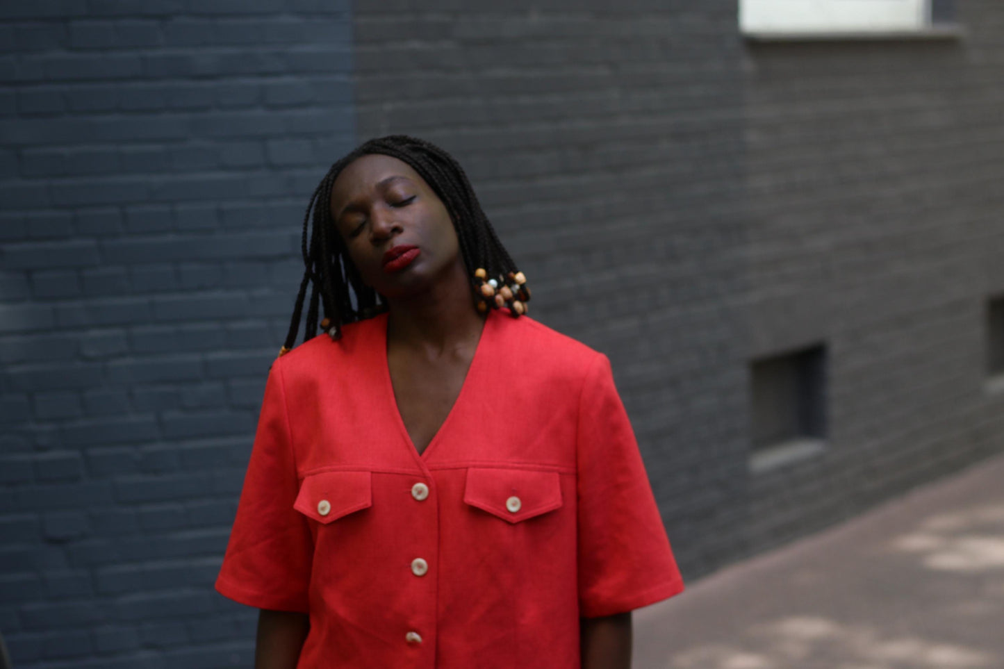 Close-up image of model wearing a vintage 90s Short-Sleeve Blazer by Mark Wald photographed in front of a grey brick wall.