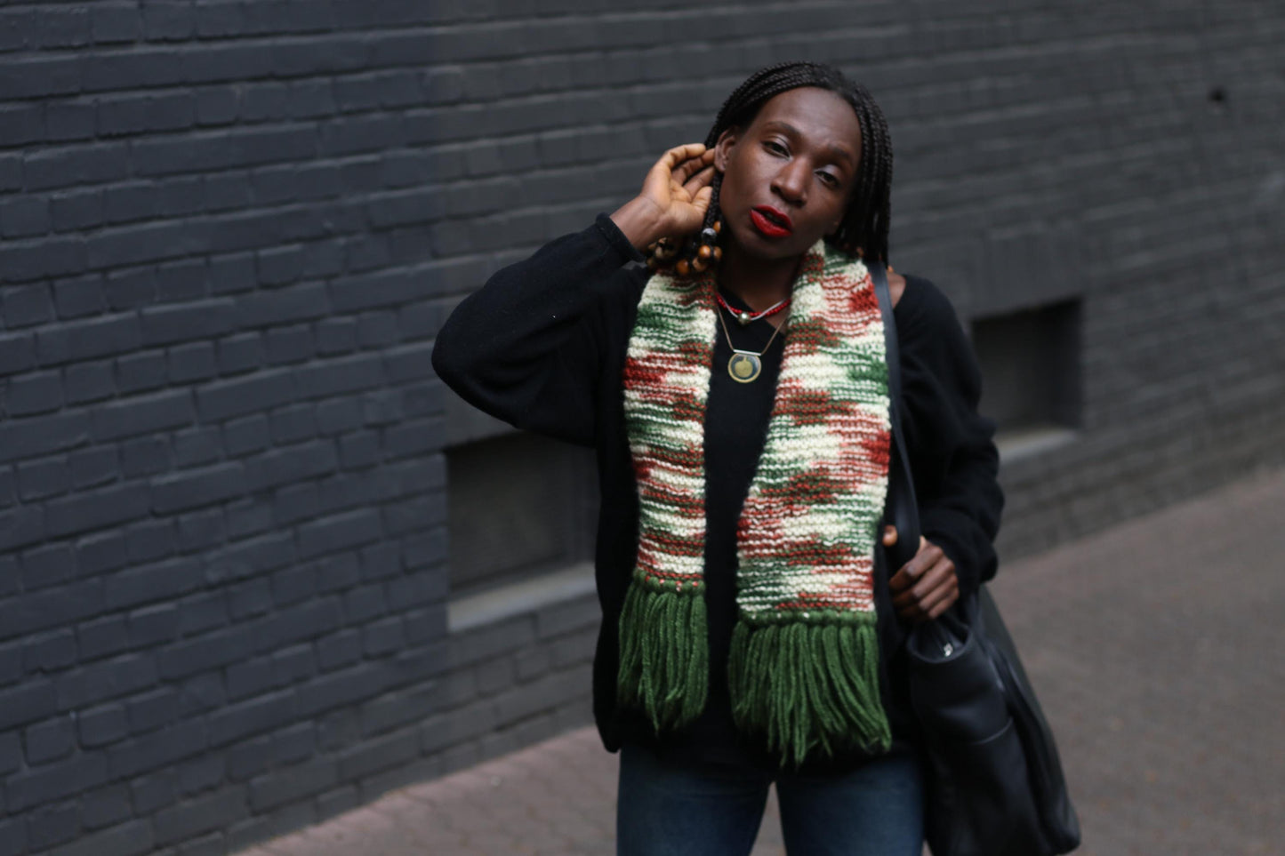 70s vintage handmade scarf with statement tassels and a retro vibe, perfect for cold weather fashion worn by a female model standing in front of a grey wall