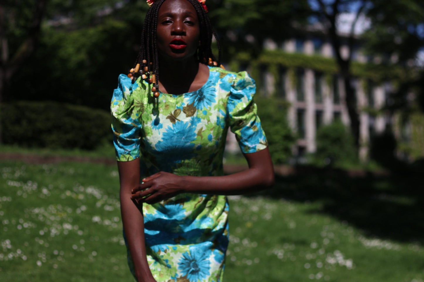 Model in a handmade floral retro dress with puff sleeves. The female model is also wearing a pink and red floral crown. The mod feminine dress is ideal for garden parties, festivals, or retro-inspired outfits.