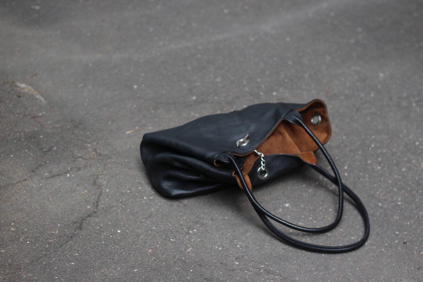 Stylish large black hobo-style bag made of leather, shown on a dark ground.