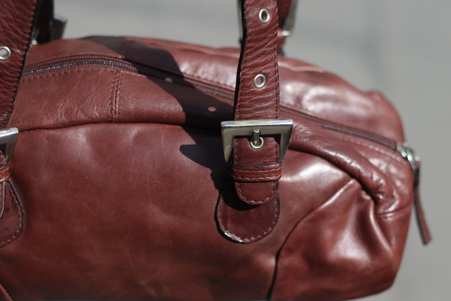 Closeup of a 90s structured leather bag in rich brown, minimal and elegant with top handles and adjustable straps