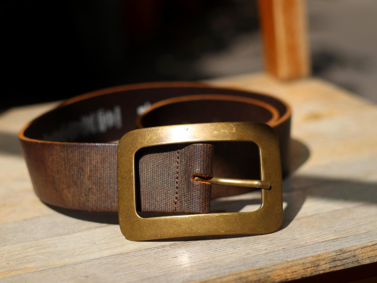Vintage brown leather belt with bold rectangular brass buckle, C&A Accessories, classic unisex style, laid on wood surface