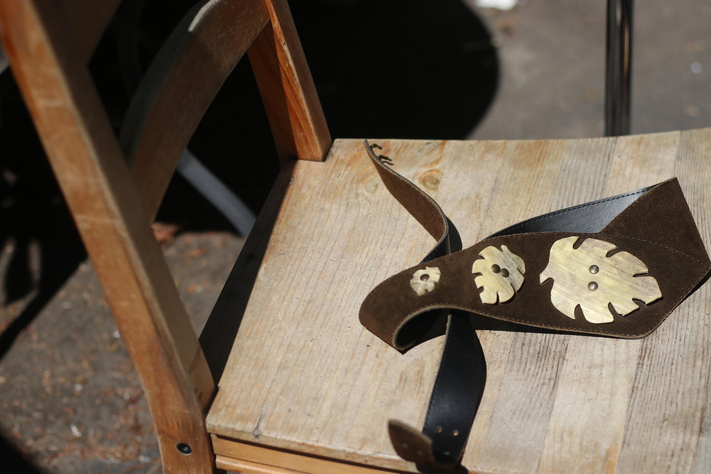 Vintage 80s Brown suede leather belt with three brass leaf appliques, a vintage from Austria with a folkloric design, shown on a wood grain background