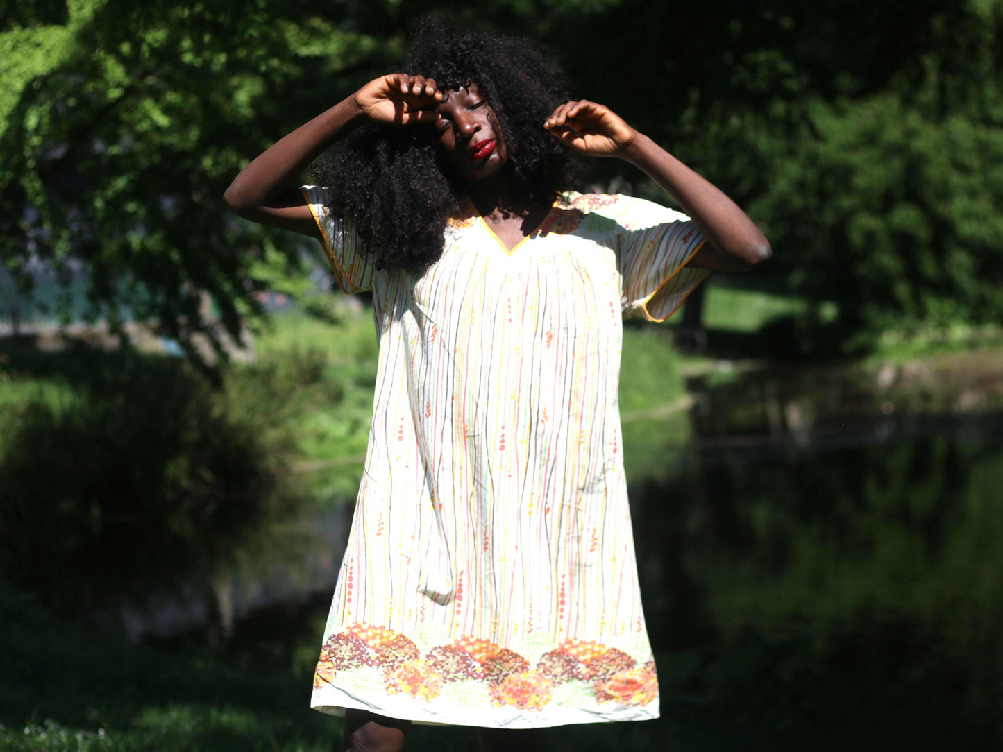 A mid-length vintage romantic prairie-style 70s dress with floral print and a v neck showcased on a female model with curly hair outdoors