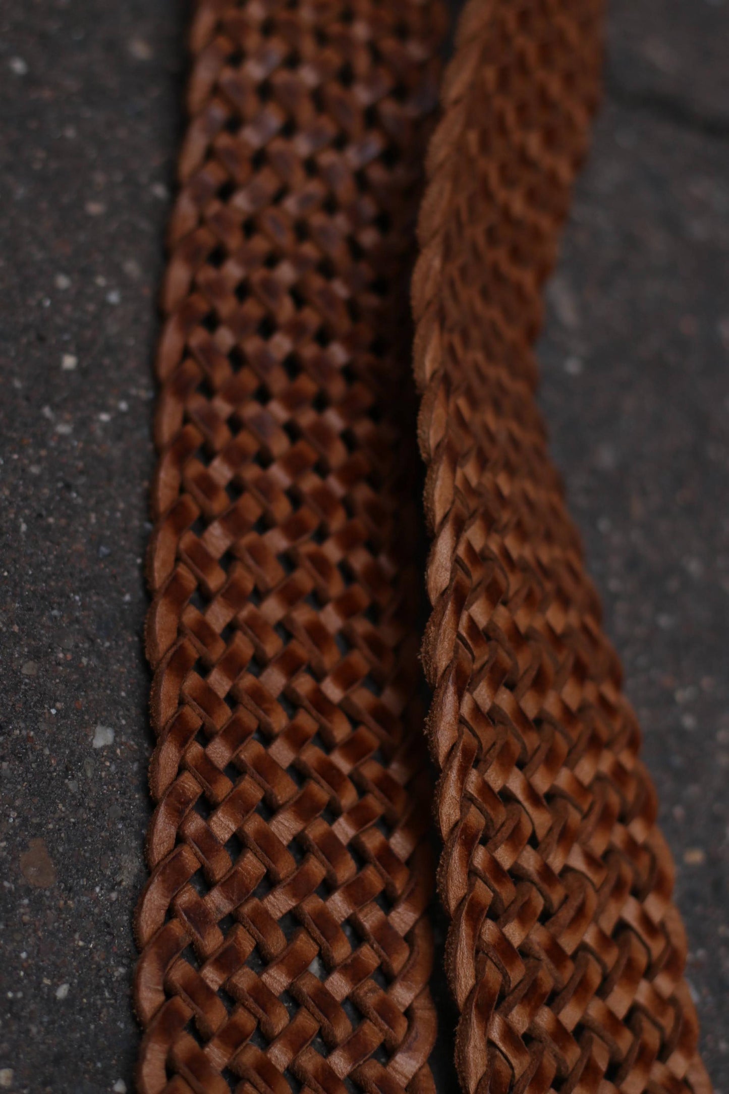 Detailed close-up of the intricate braiding on the brown leather belt.