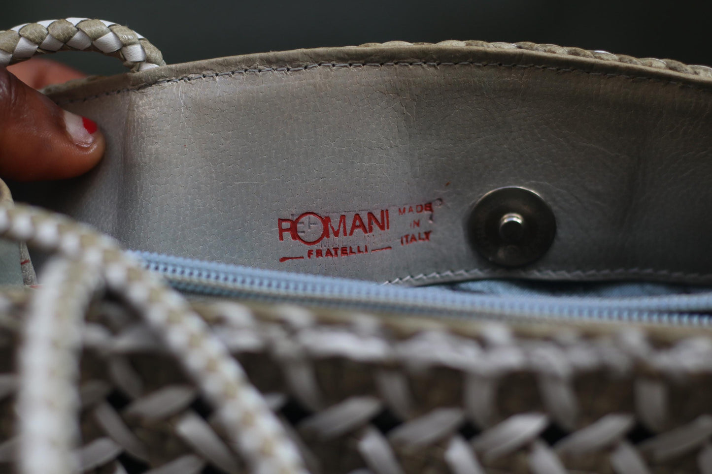 Inside of a White leather woven bag by the following is visible in red lettering: Romani Fratelli Italy