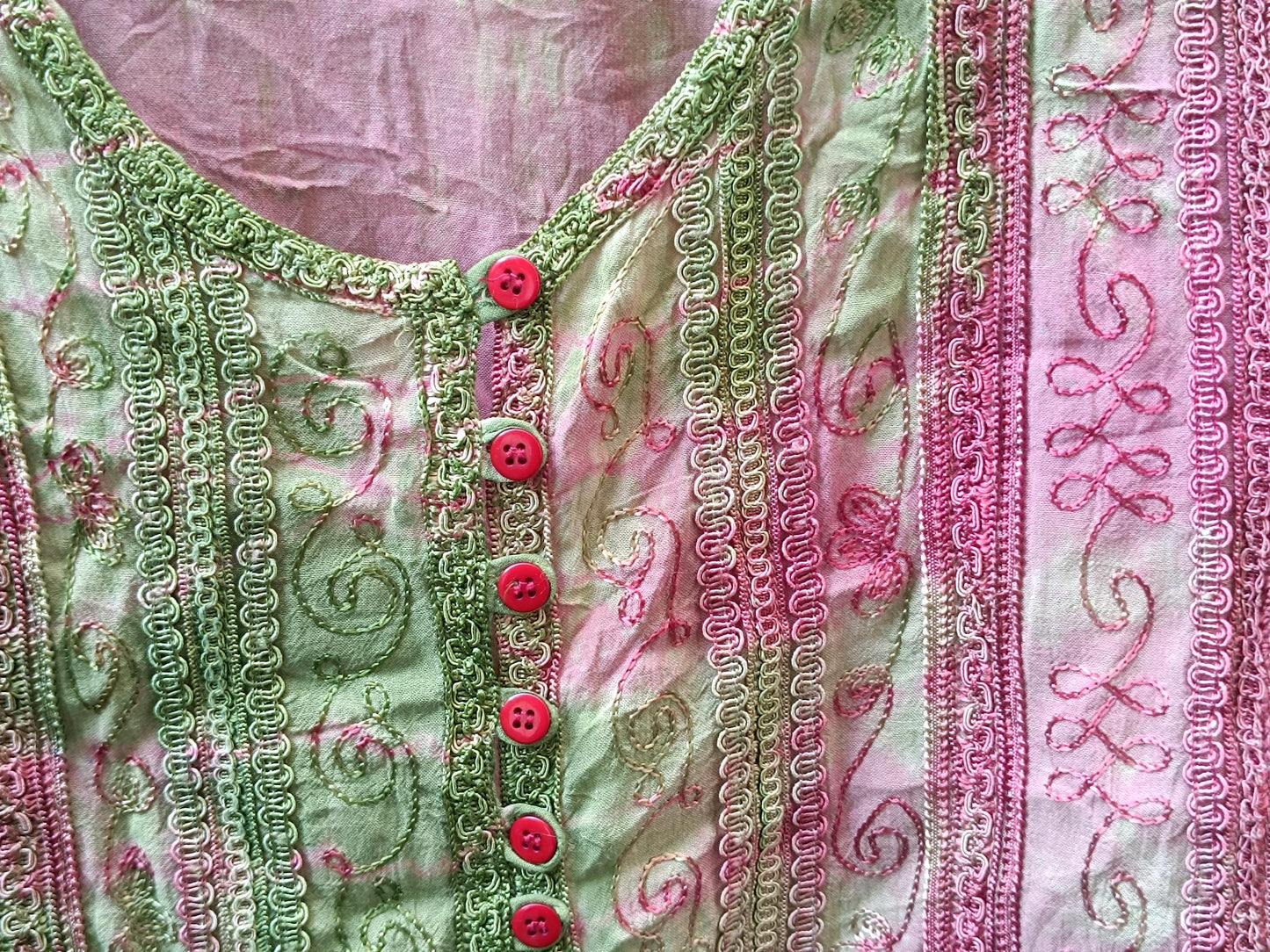 Close-up detail of the vintage 90s boho chic top with pink and green patterned fabric with unique stitching and red button accents