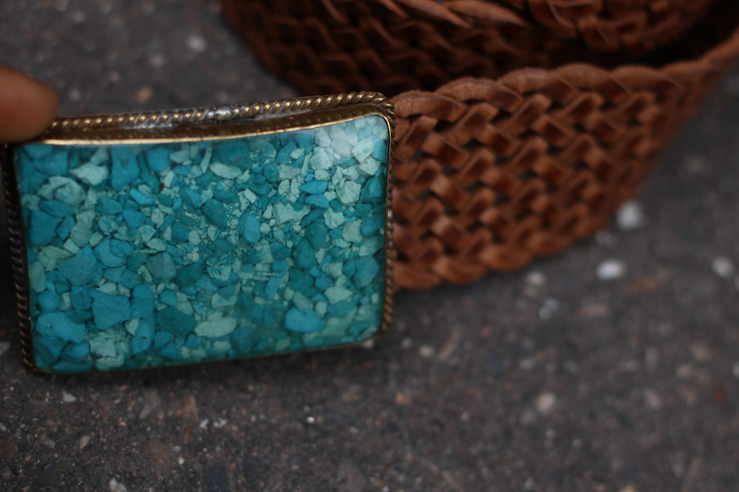 A segment of a vintage brown braided leather belt with the turquoise buckle resting beside it.