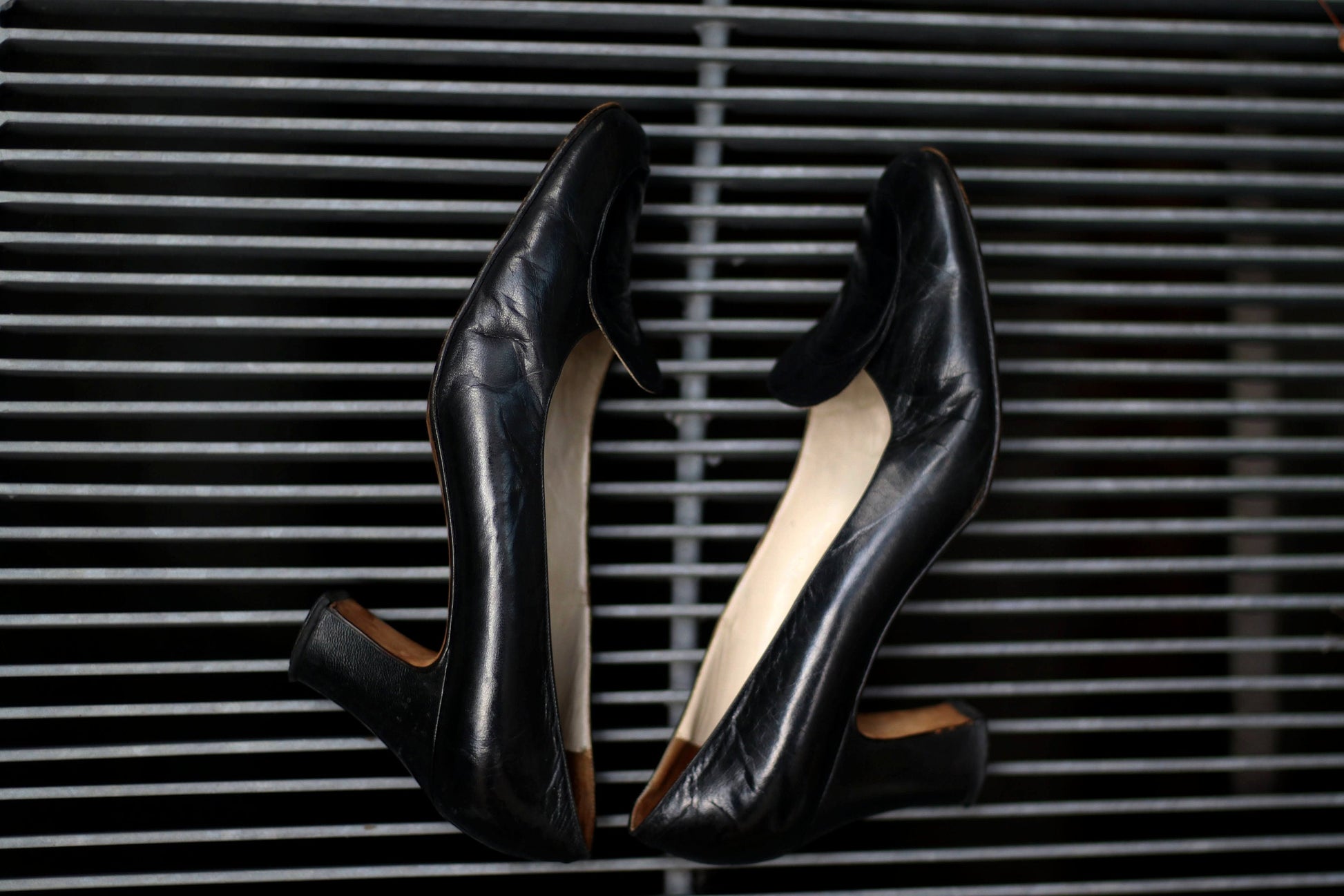 Vintage black leather high-heeled shoes with a rounded toe and mid heel, showcased on a concrete surface. Perfect for retro fashion enthusiasts and classic footwear collectors.