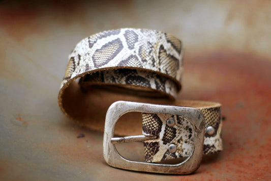 Close-up photo of a fashionable snake print leather belt with a vintage metallic buckle. Perfect accessory for trendy outfits and stylish looks.