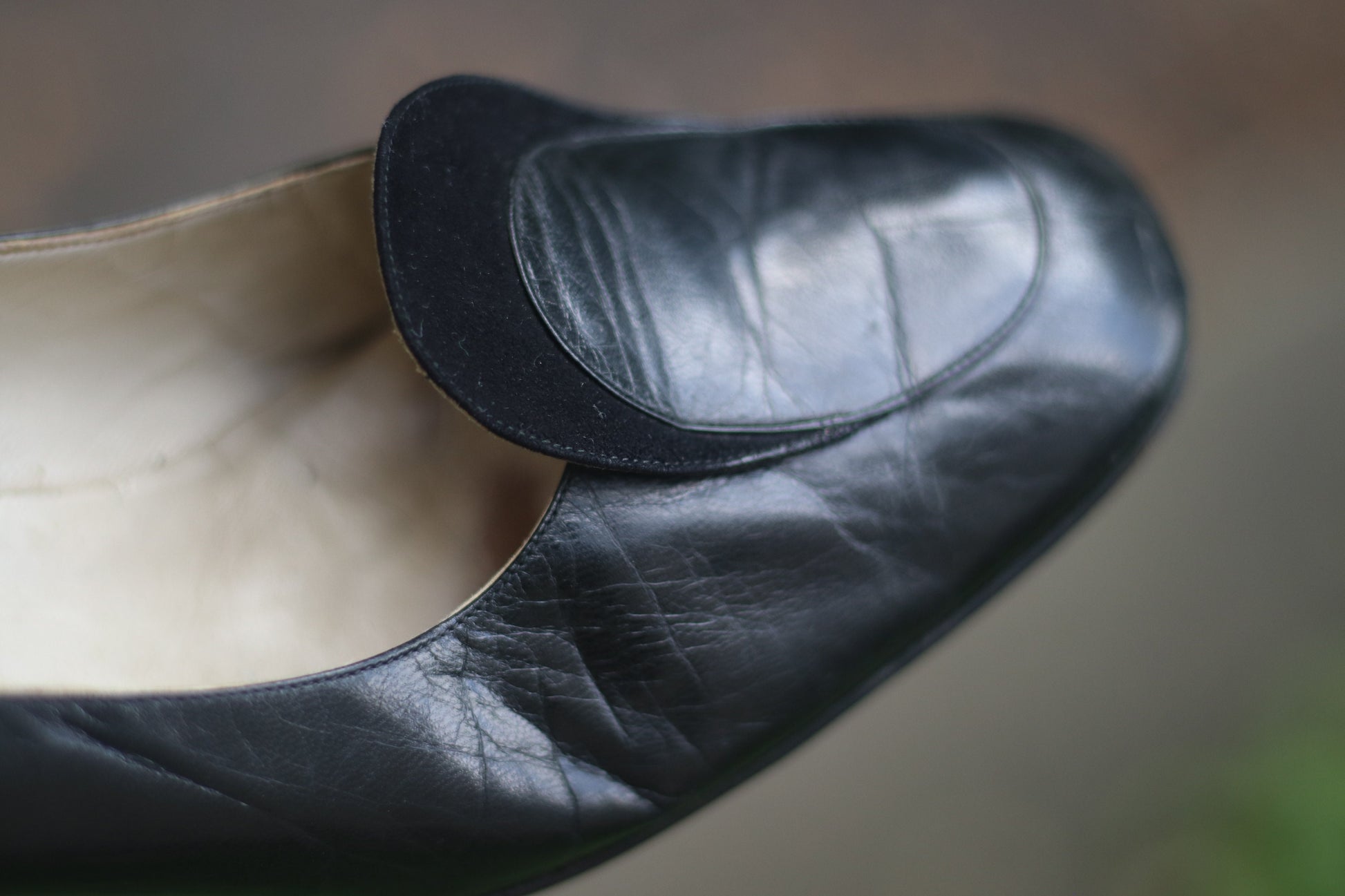 Vintage black leather high-heeled shoes with a rounded toe and mid heel, showcased on a concrete surface. Perfect for retro fashion enthusiasts and classic footwear collectors.