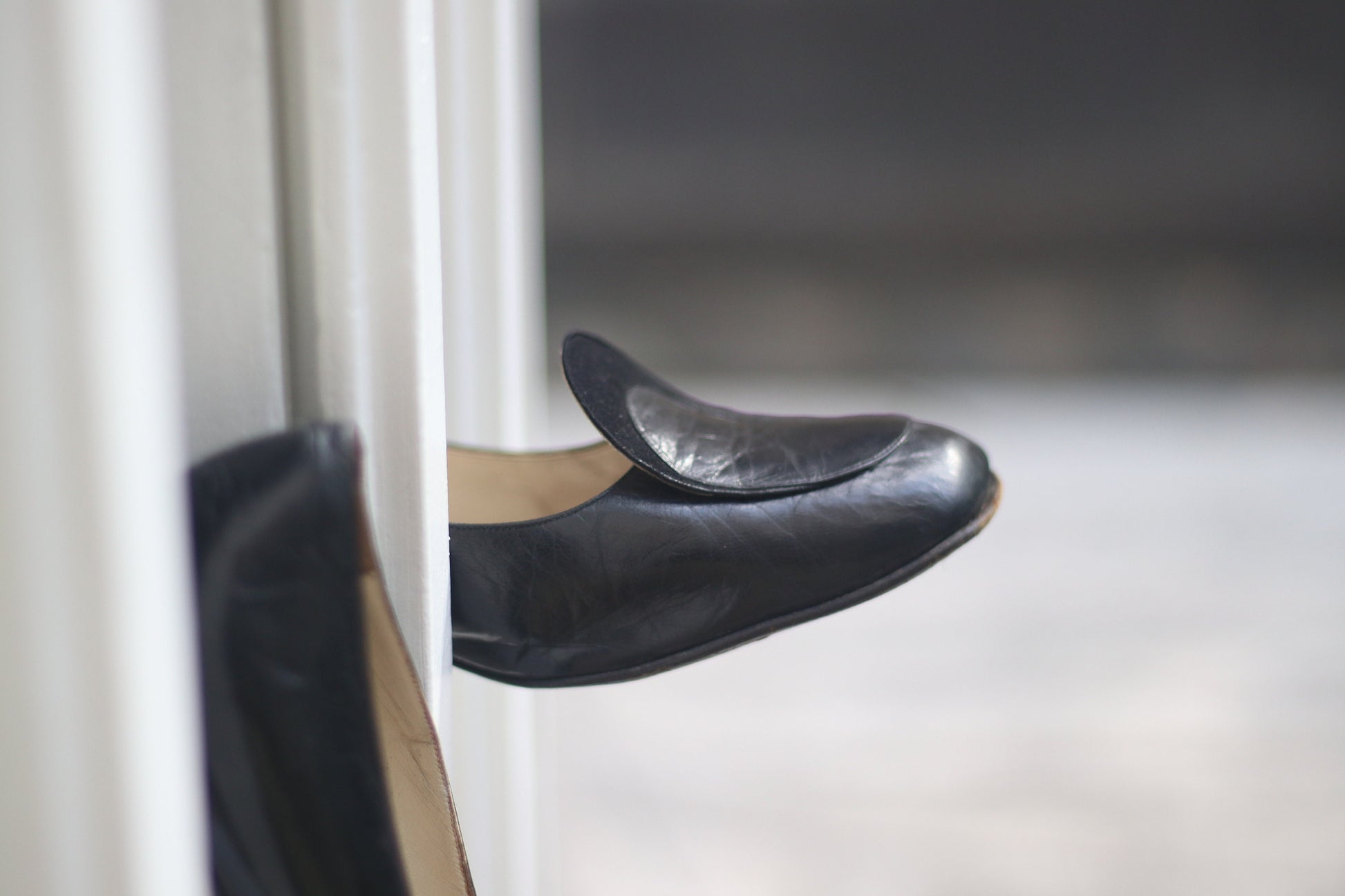 Vintage black leather high-heeled shoes with a rounded toe and mid heel, showcased on a concrete surface. Perfect for retro fashion enthusiasts and classic footwear collectors.