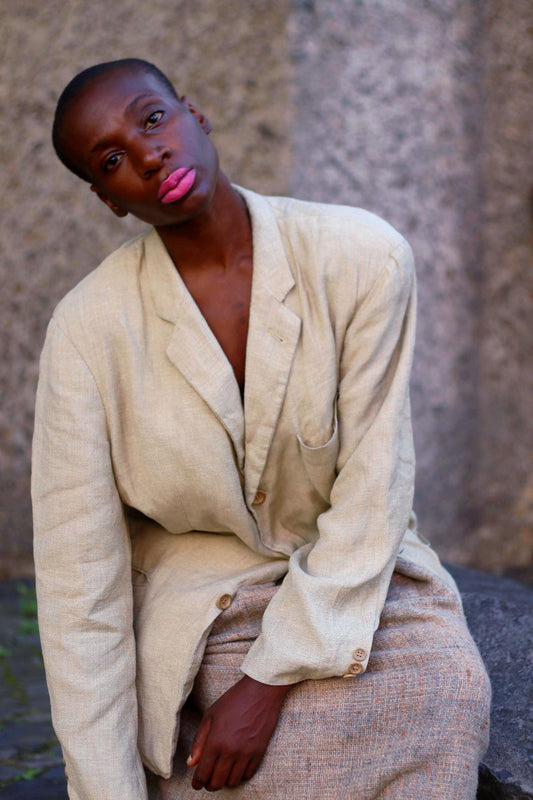 Model of African Heritage wearing a vintage Hugo Boss beige linen blazer  against a textured stone background, portraying a unique fashion style.