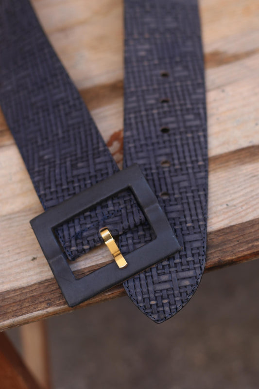 Vintage blue belt with a Woven Optic Finish and oversized buckle is photographed on a brown wooden chair