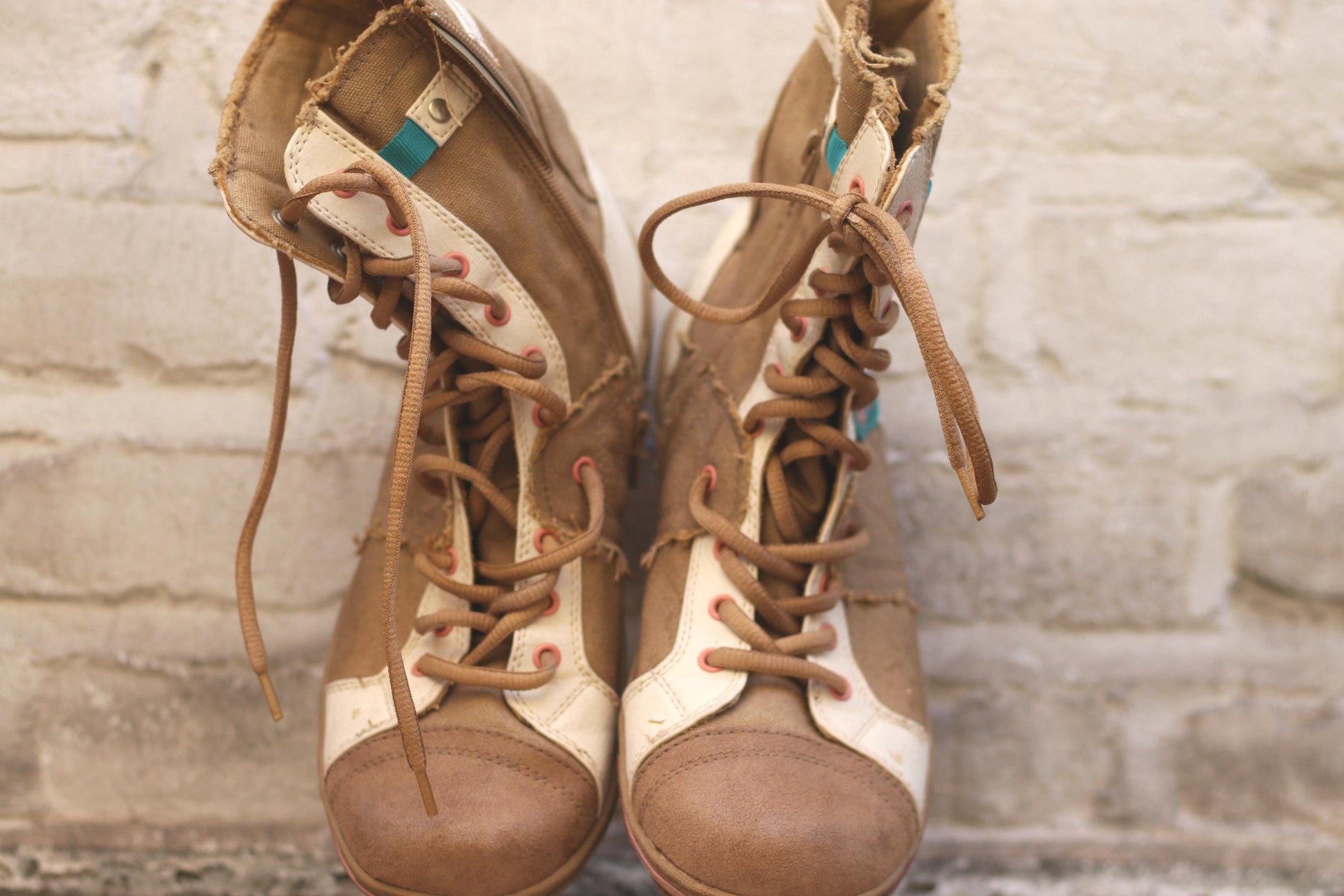 Vintage brown and beige canvas high-top sneakers with a blue leaf design, placed on a wooden chair in a rustic setting. Perfect footwear for a casual, retro-inspired style.