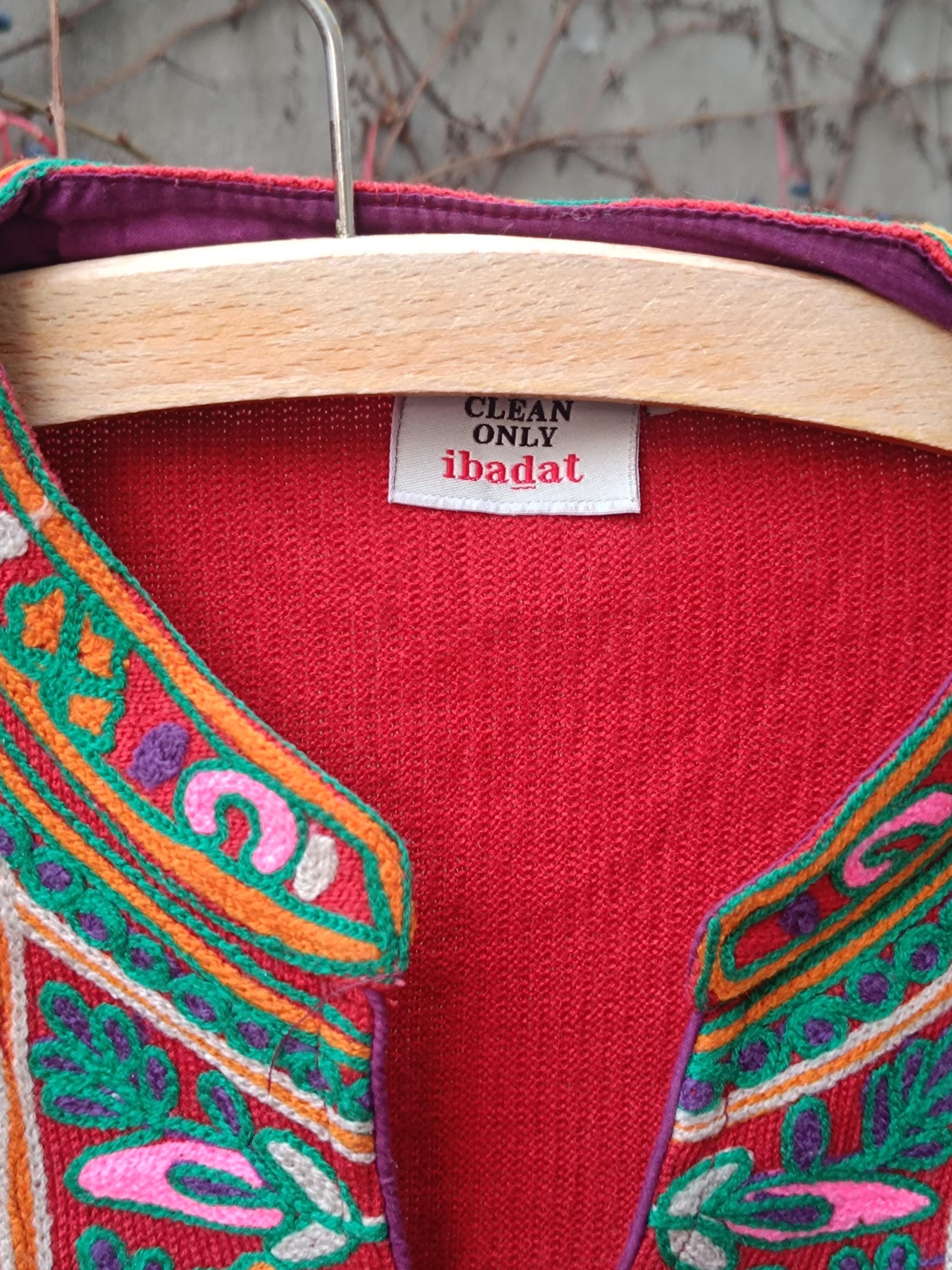 A close-up image of a folk-style red dress with colorful embroidered flowers and keyhole neckline. The photo zooms in on the bohemian feel by highlighting the floral details by the neckline