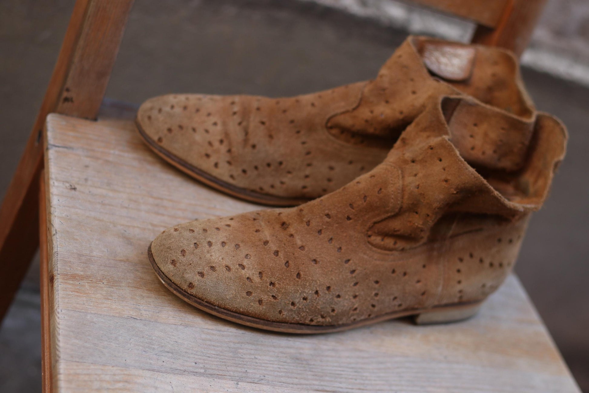 Vintage Tommy Hilifger brown suede ankle boots with perforated design, placed on a wooden surface. Vintage fashion footwear, rustic aesthetic.
