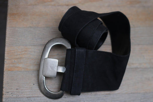 Close-up of a stylish black leather belt by Marc Cain. The vintage belt touts  a silver buckle and is photographed on a wooden table. Perfect fashion accessory for enhancing outfits with a touch of elegance and sophistication.