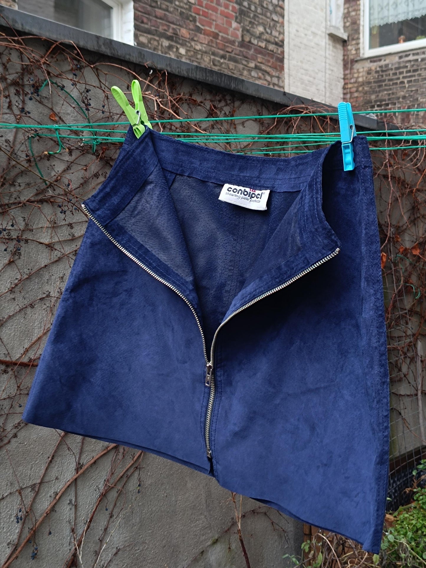 A dark blue suede skirt with a zipper up the front. The skirt has a label that says &#39;conbipel&#39;.