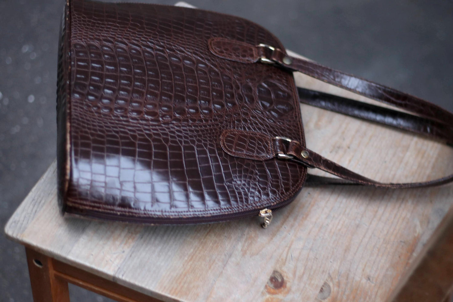 70s Vintage dark brown embossed leather shoulder bag on a wooden surface.