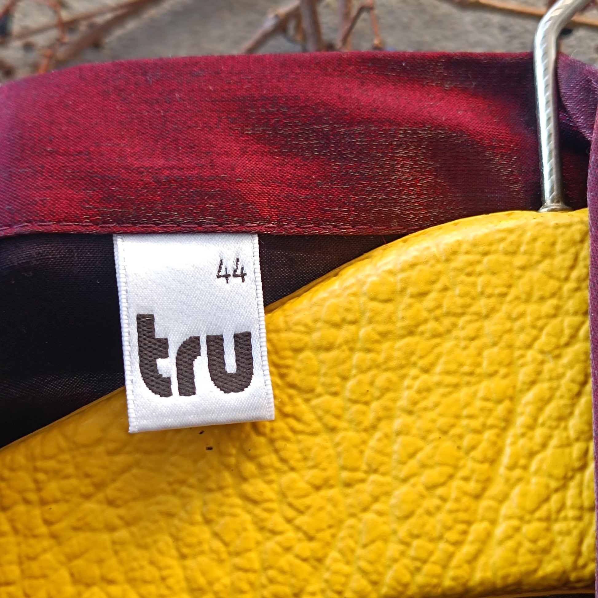closeup of the brand tag of the glossy red Y2K vintage blouse. Tag reads Tru and size 44 is also displayed