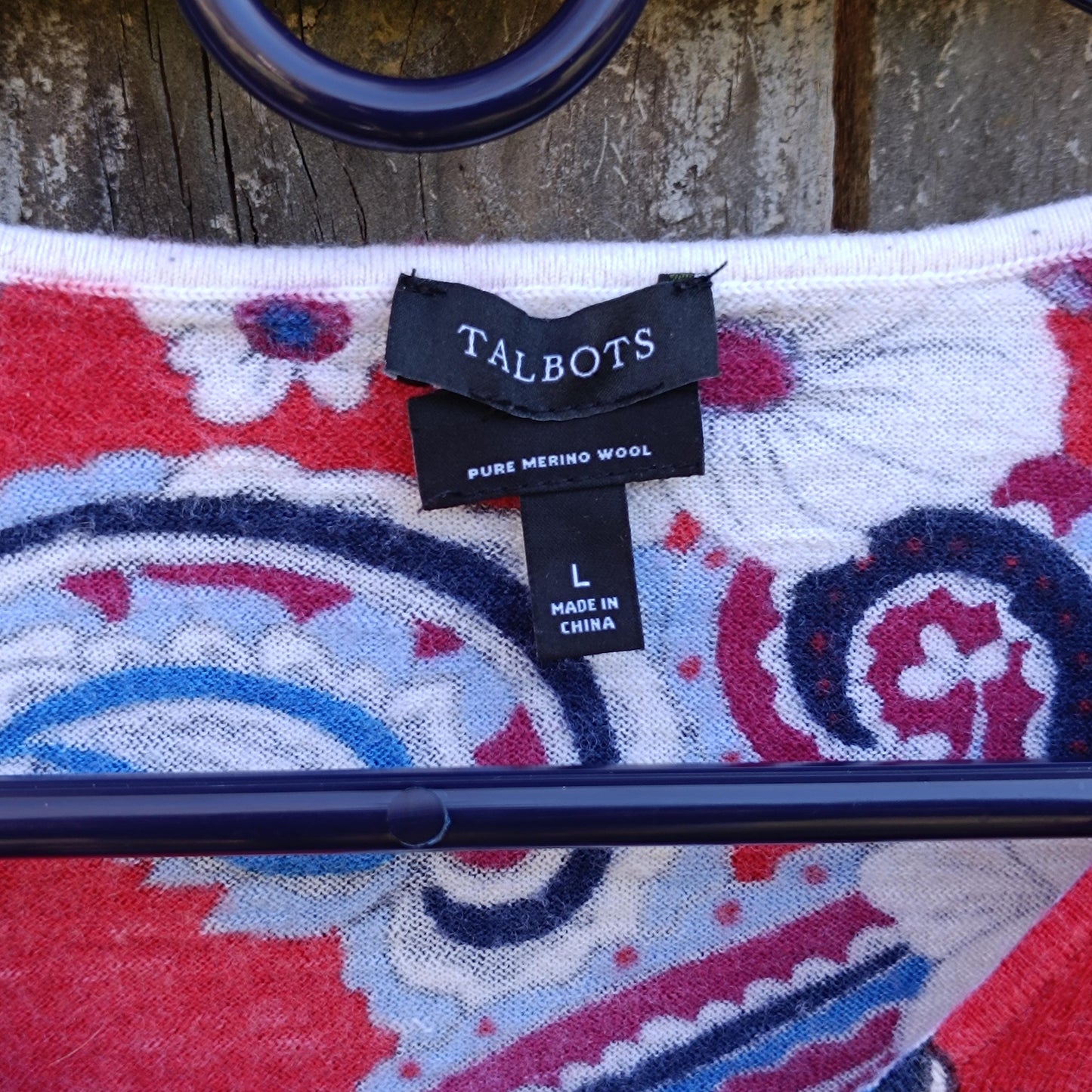 An image of a the brand tag of a  vintage merino wool Talbot's blouse. The black tag reads: Talbots and information about the size is also visible