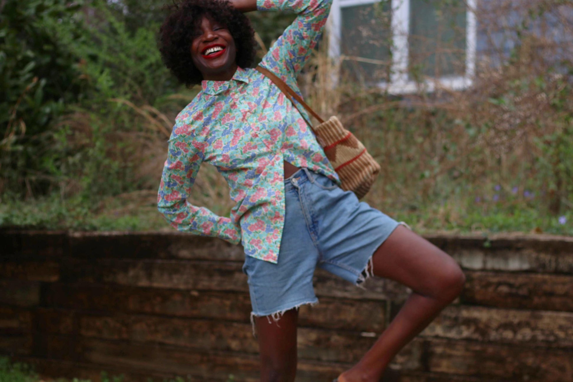 Capturing cottagecore charm, a woman showcases a vintage J.Crew floral print shirt. The cotton blouse features a button-up front and pointed collar, its soft pastel florals exuding a nostalgic, garden-inspired feel against a green background