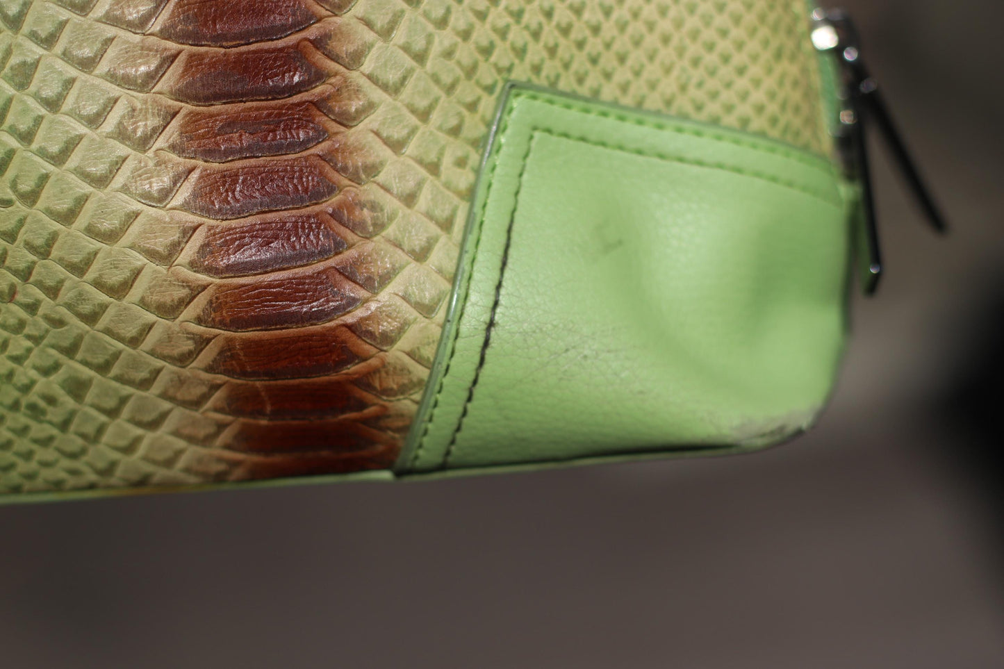 A detailed close-up of an 80s vintage, light green faux leather handbag featuring an animal print stripe in brown and reddish tones, highlighting the textured material and the unique shape of the rounded handles.