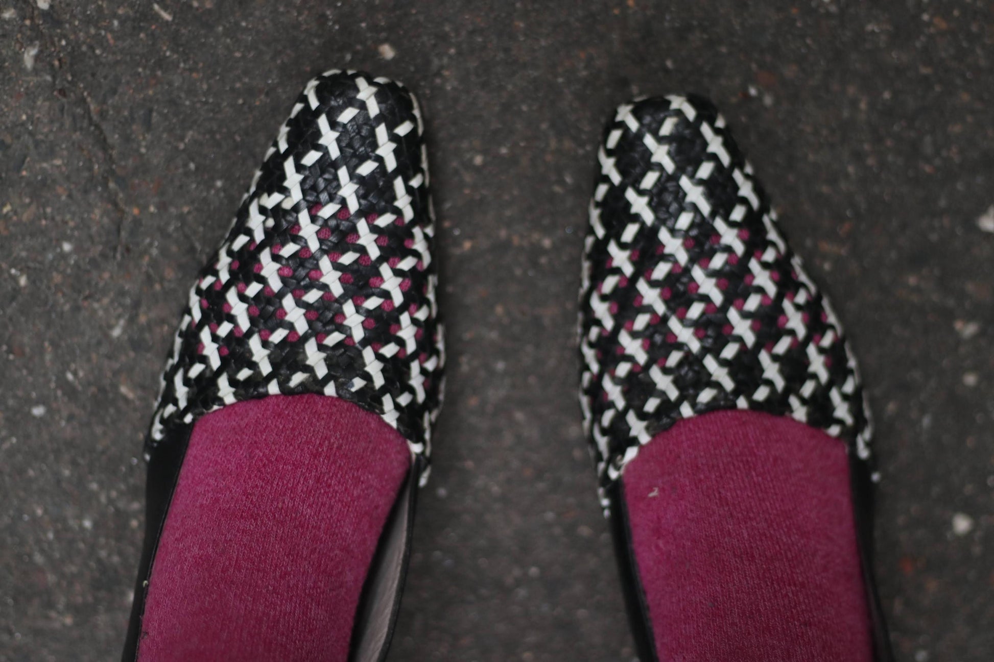 a pair of vintage Alexandria Italian-made woven slingback pumps featuring a black-and-white basket-weave design, pointed toe, and block heel. The 90s design is showcased on two feet with pink socks