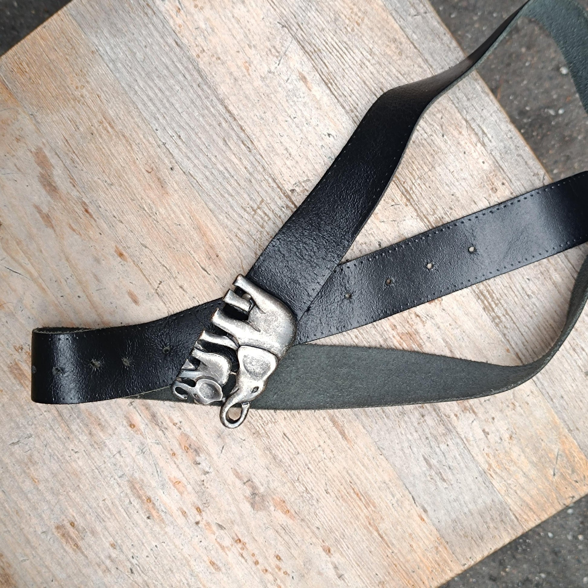 A top view of a black ethno chic  Elephant buckle belt leather belt. The vintage handmade design showcases boho chic aesthetics and mystical animal symbolism.