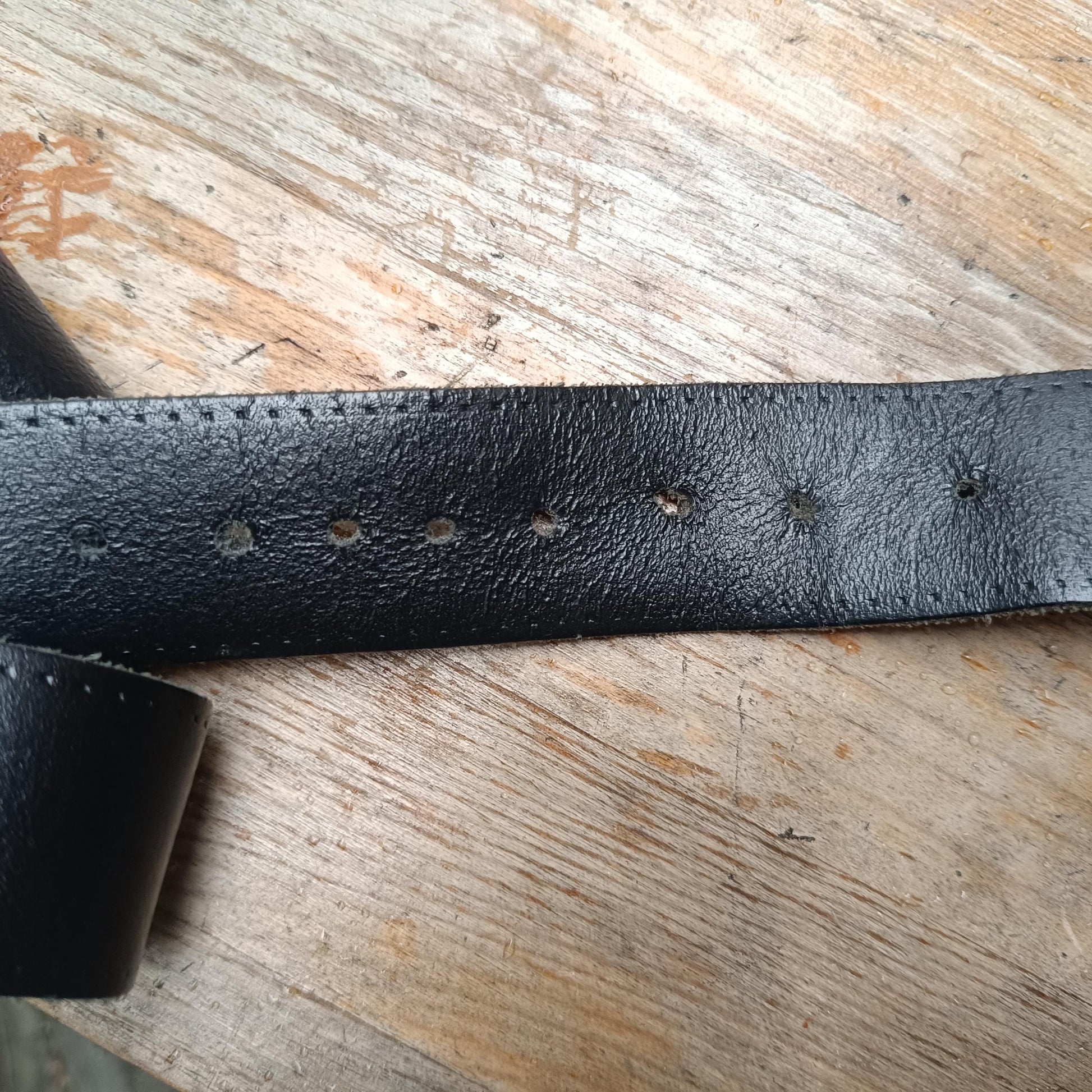 Zoomed in shot of the belt holes of the vintage leather belt with a silver antique elephant buckle.