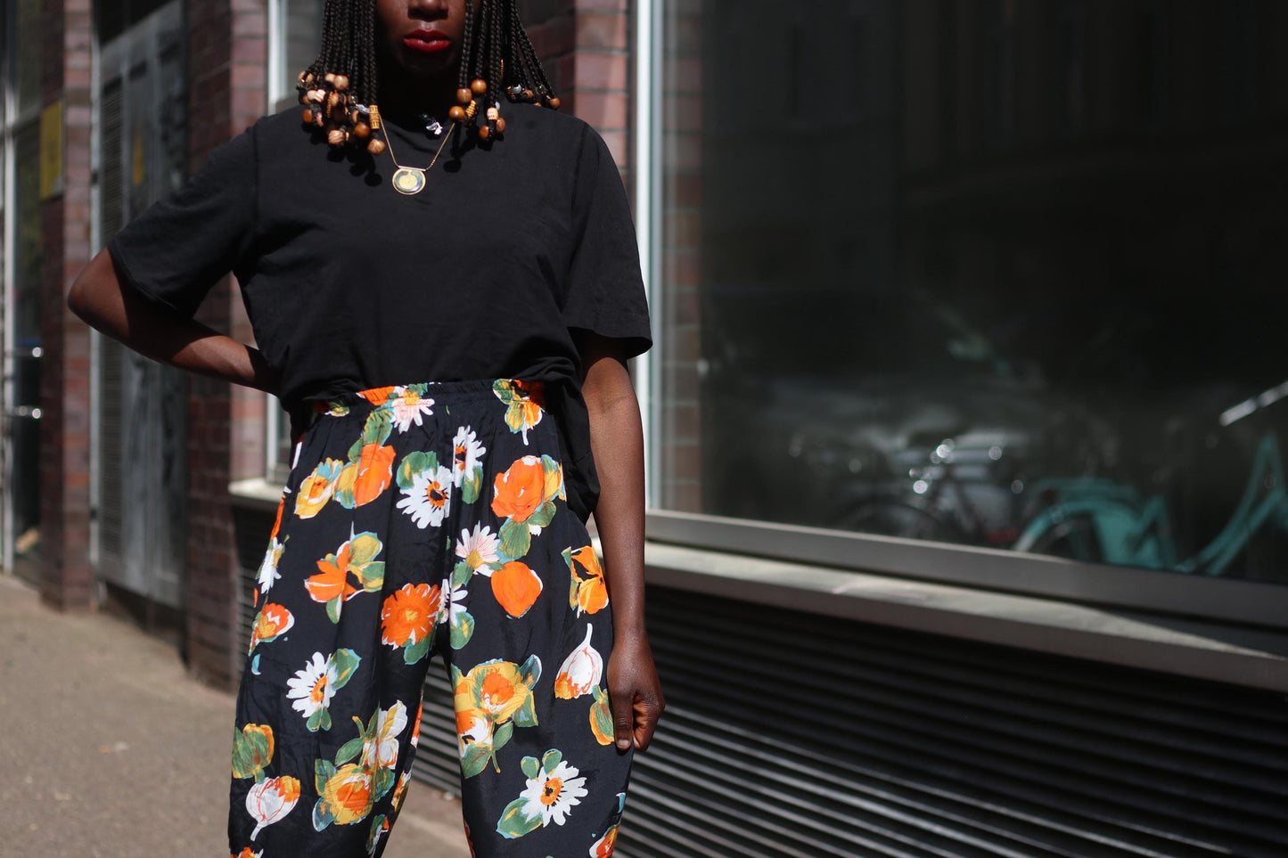 Close-up of a bold floral vintage capri pants worn casually with a loose black tee, styled for summer on a  female model with a mix of retro fun and 90s fashion vibes.