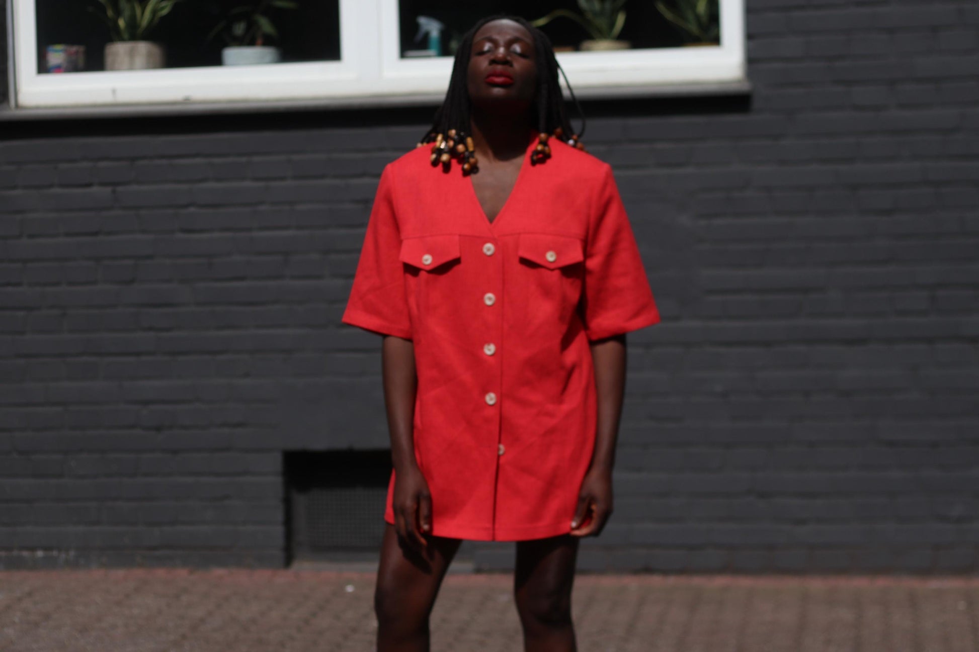 Female model in a vintage 90s Short-Sleeved Blazer by Mark Wald worn as a mini dress photographed in front of a grey brick wall.  The image highlightd the bold v-Neck Jacket as a lightweight versatile retro piece